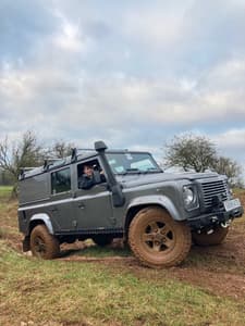 a 4 x 4 land rover driving up a muddy slope as part of an off road driving experience