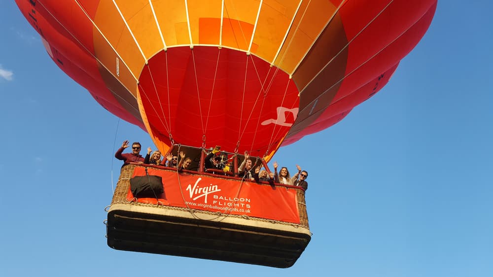 a red virgin balloon flights hot air balloon taking off against a blue sky