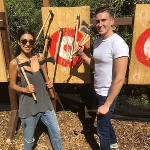 man and woman posing with axes in front of targets on an axe throwing experience