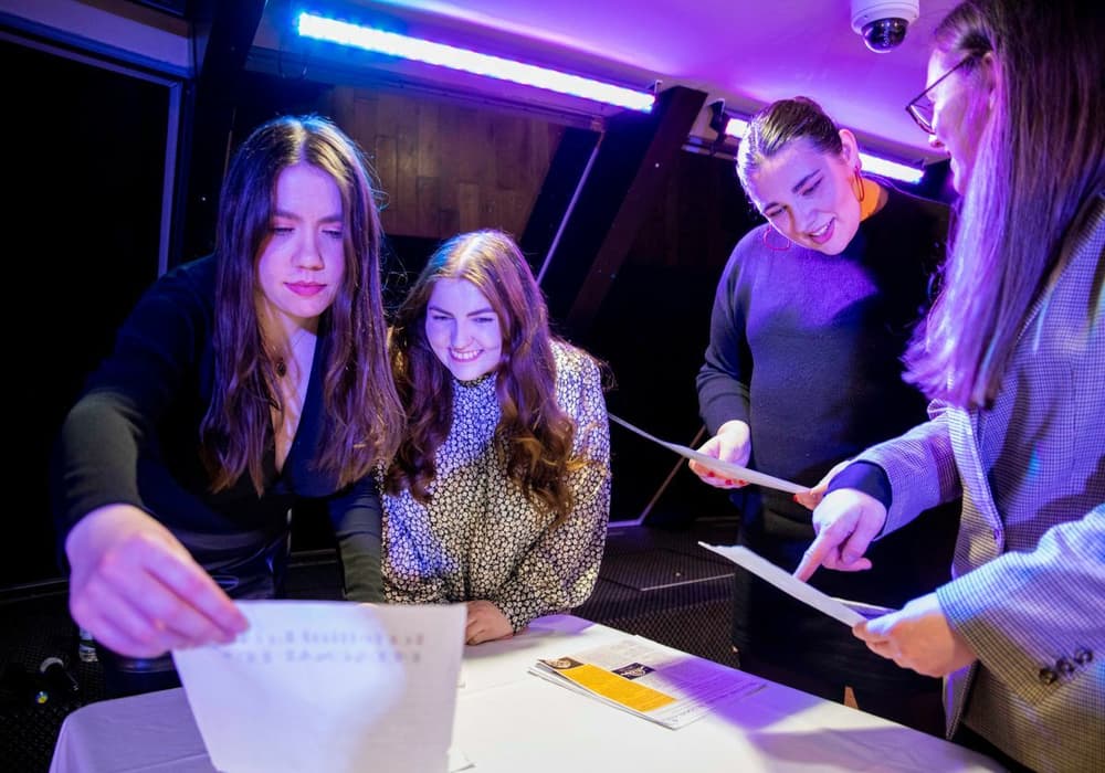 A group of girls looking at clues on the Murder Mystery river cruise