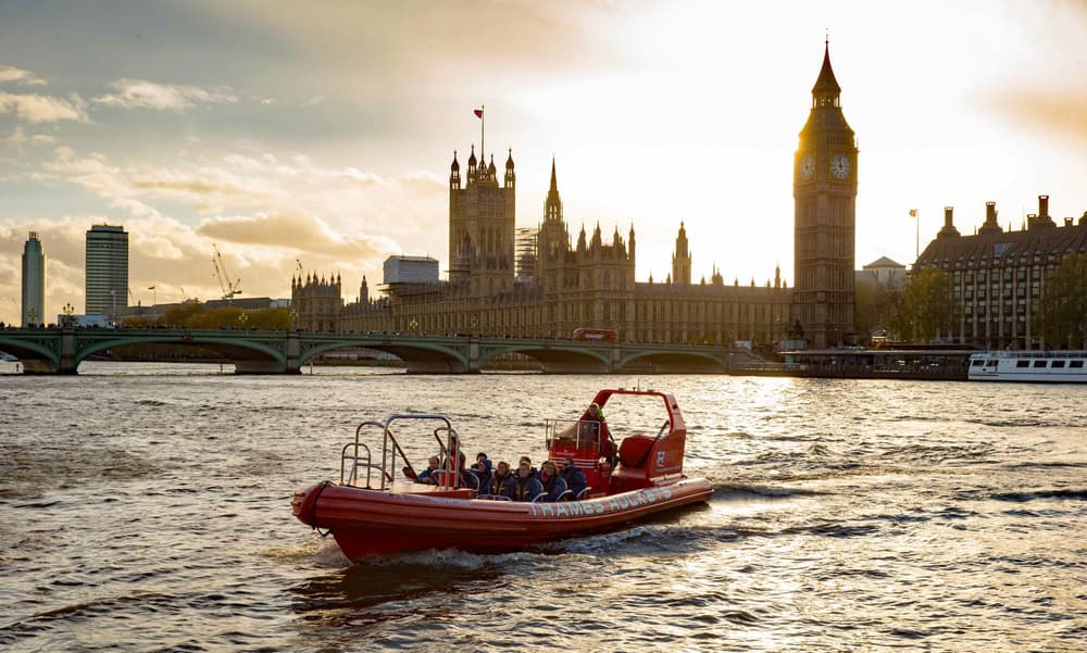 a thames rockets speedboat on the river thames in the evening with the sun setting behind the houses of parliament