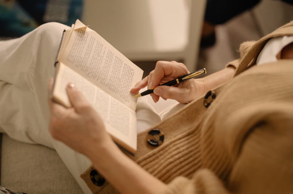 Lady writing at a table with a glass of wine
