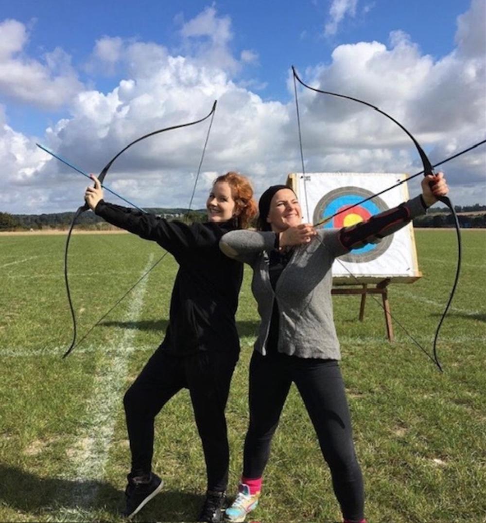 2 girls posing with bows for archery