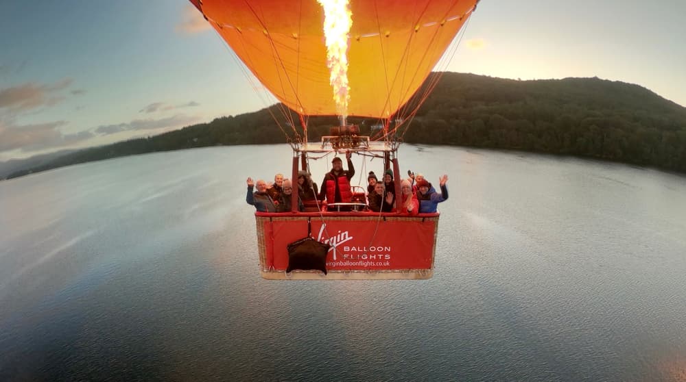 a hot air balloon flying over a lake in lancaster