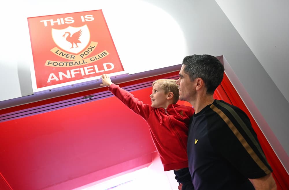 father and son looking up at the this is anfield sign on the liverpool fc stadium tour
