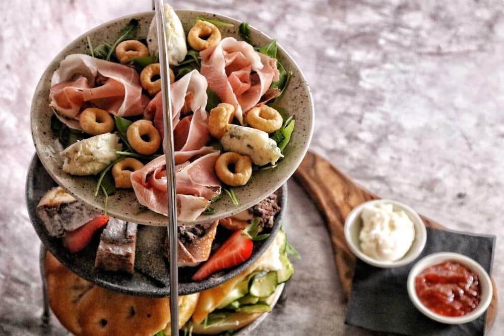 an afternoon tea display stand filled with cured meats, bread and cheese with dips on the side for an afternoon tea gift experience