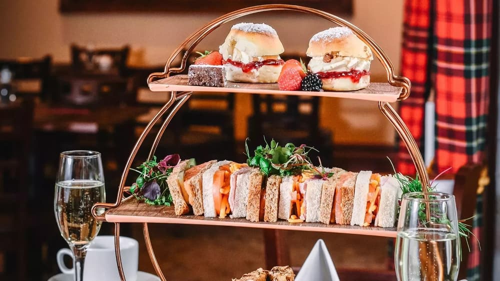 an afternoon tea displayed on a tiered stand with sandwiches and scones