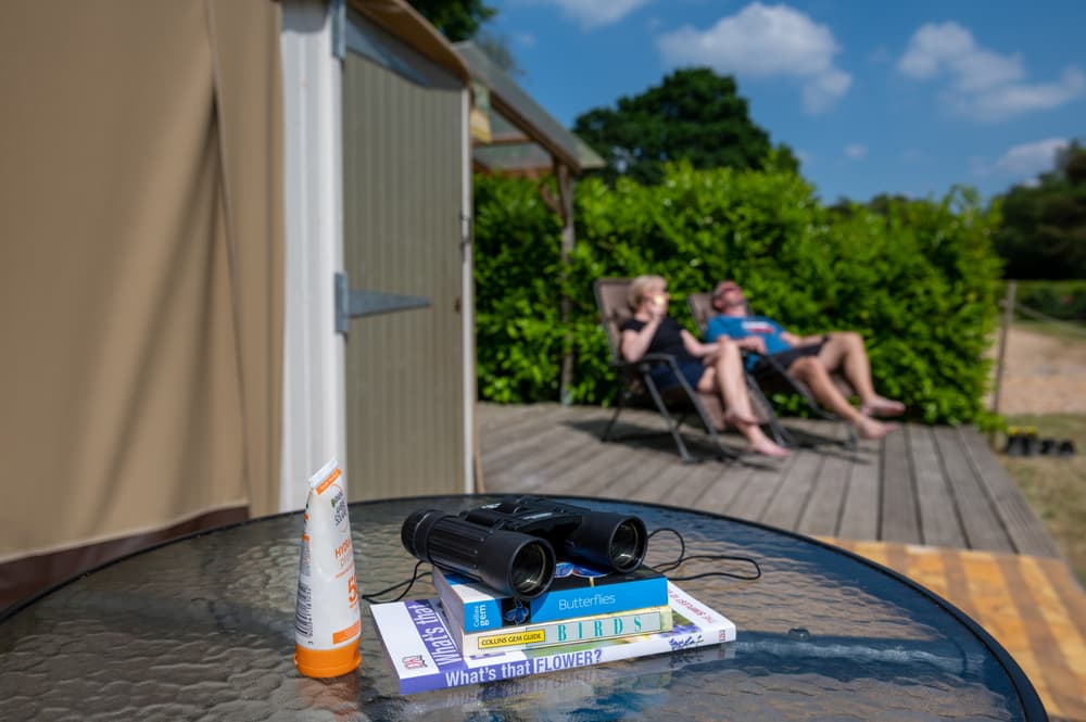 couple relaxing in the sun outside the yurt at back of beyond glamping in dorset