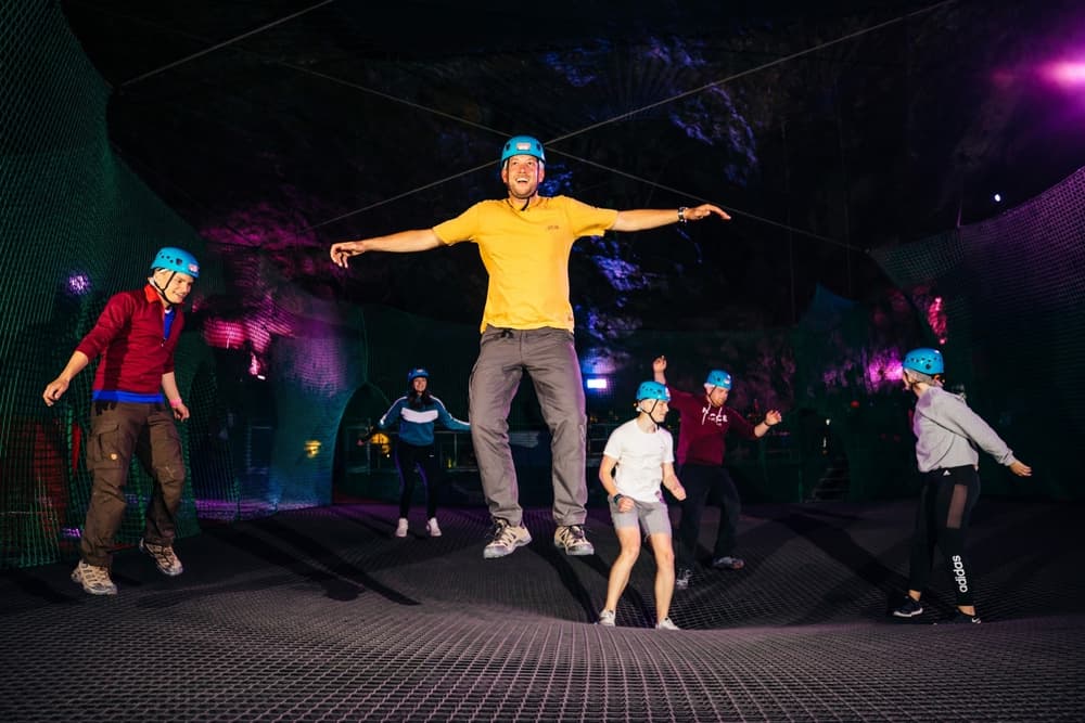 people bouncing on a trampoline inside a cave on a bounce below experience day