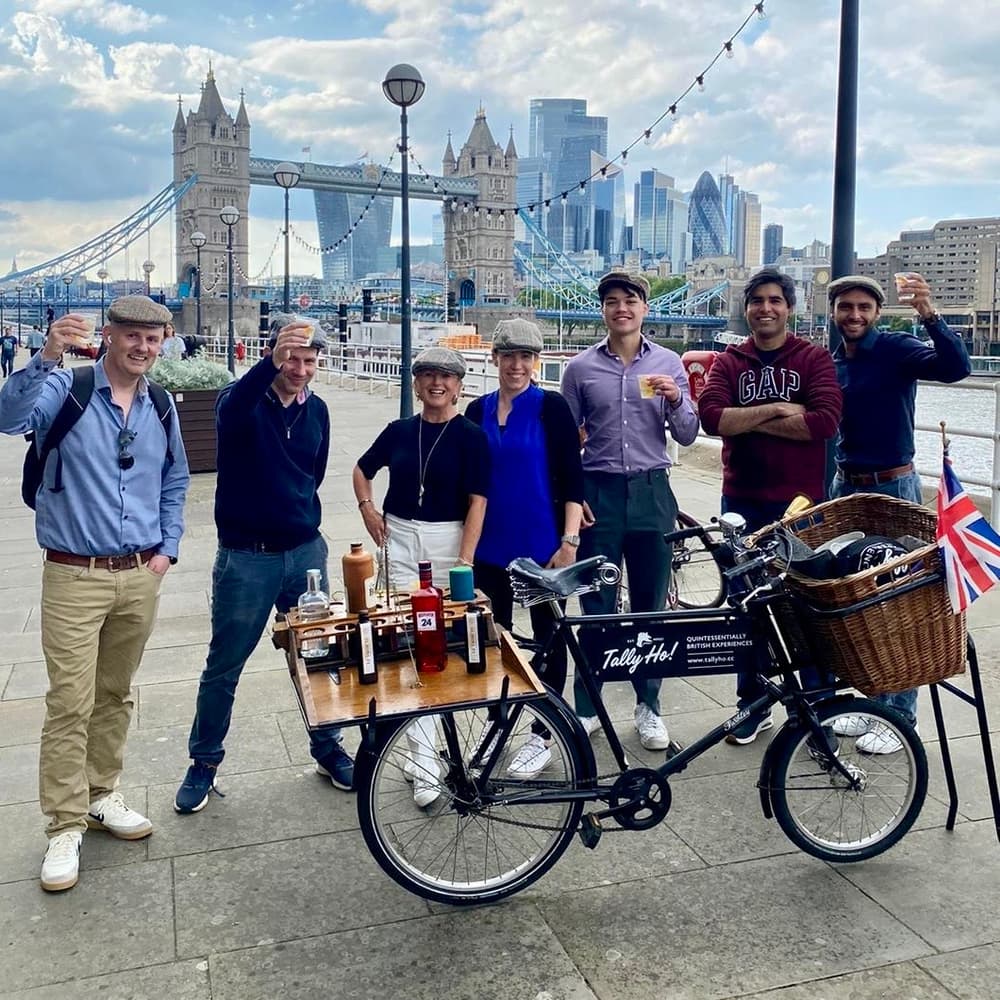 group of people standing next to vintage bicycles in front of tower bridge on a gin bike tour