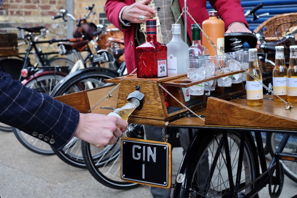 person opening a bottle on the back of a bicycle loaded with bottles of gin on a gin bike tour
