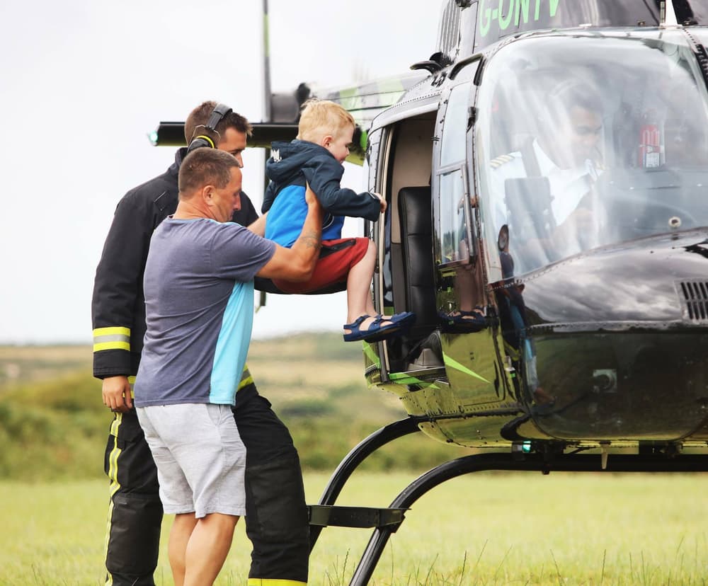 a man helping a child into a helicopter as part of a helicopter family experience