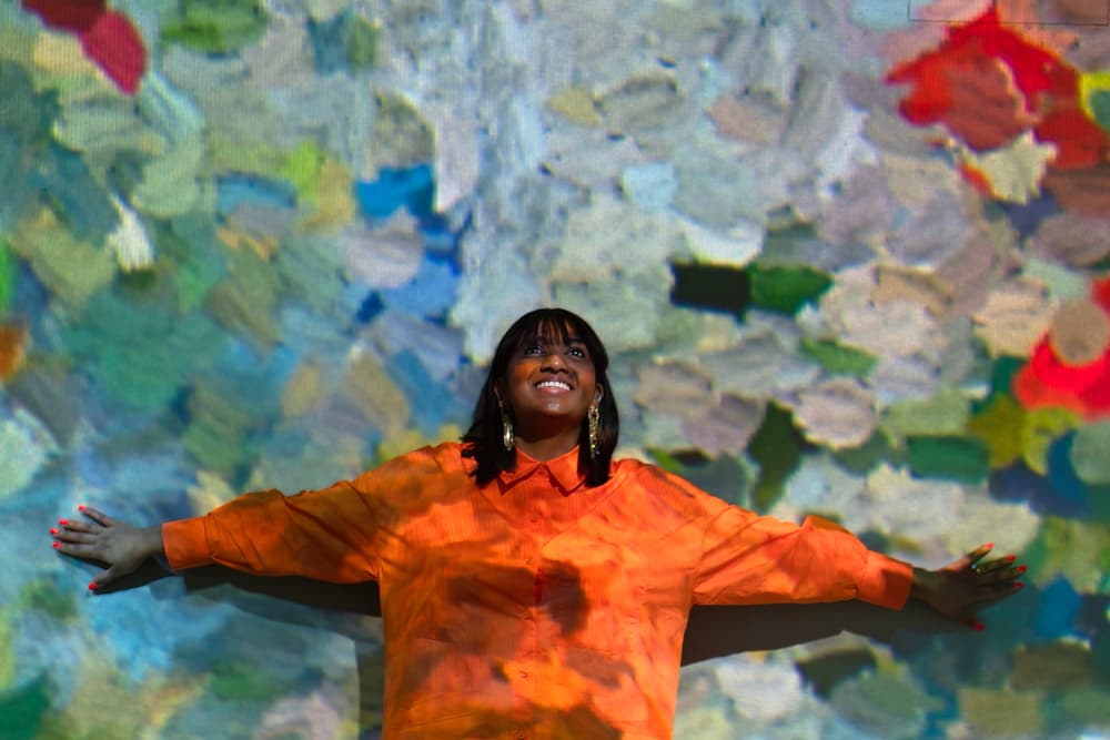 woman standing against a wall at the frameless immersive art exhibition in london