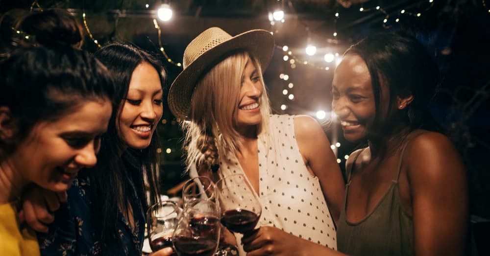 four women enjoying a night out with glasses of wine on. a galentines night out