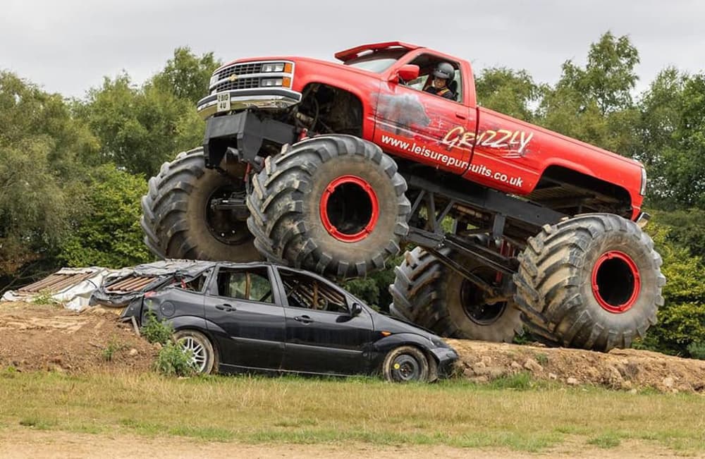 an american monster truck being driven over a car on a monster truck driving experience