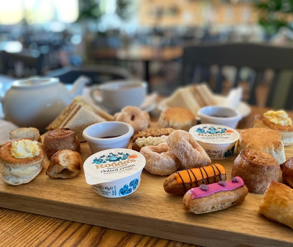 an afternoon tea spread with sandwiches, cakes and scones and pot of tea