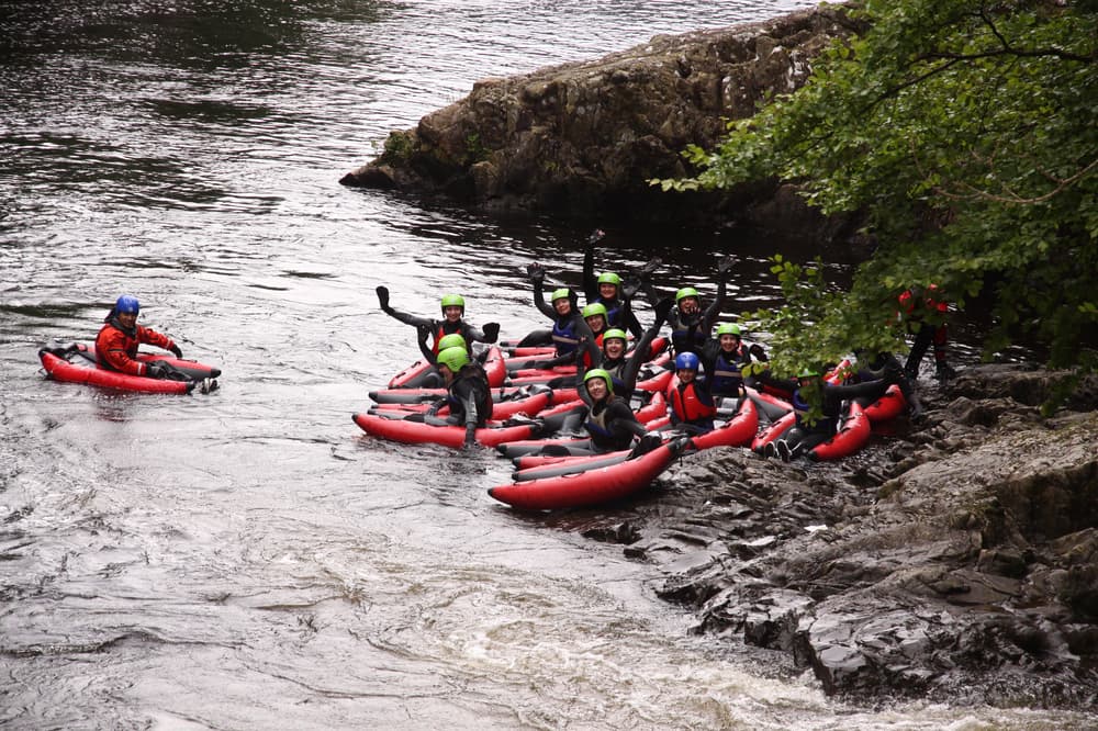 group of people on the side of a river getting ready for a river bugging experience on the river tummel in scotland