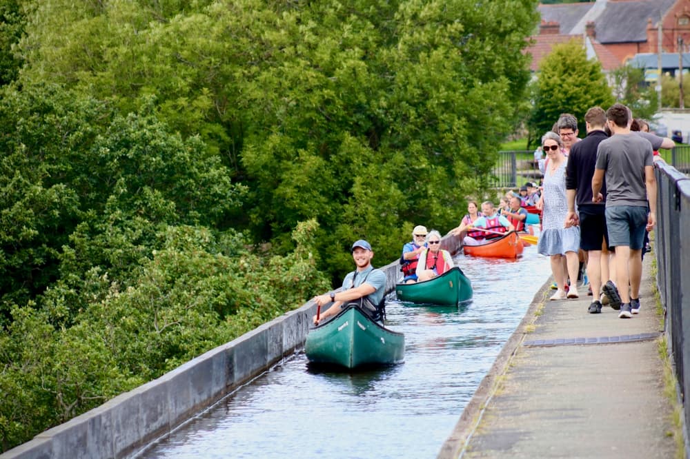 people in canoes going along an aqueduct in wales