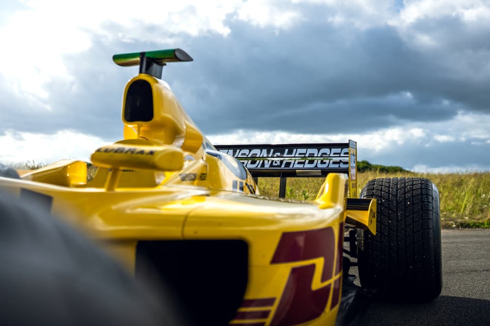 close up shot of the front of a yellow jordan f1 race car with dark clouds overhead