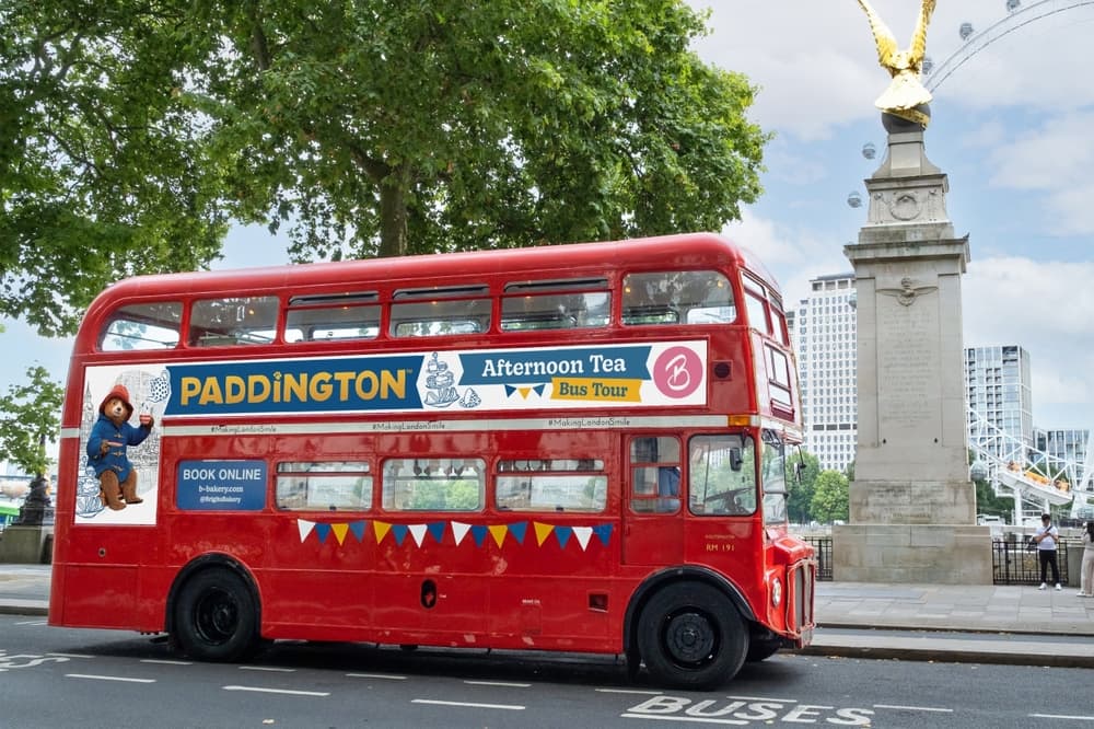 the red double decker paddington afternoon tea tour bus driving through london