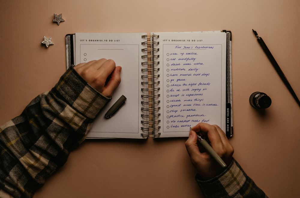 a piece of paper with new years resolutions written on it resting gold paper with snowflakes on