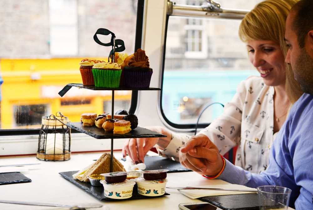 couple enjoying afternoon tea on the red bus bistro afternoon tea bus tour
