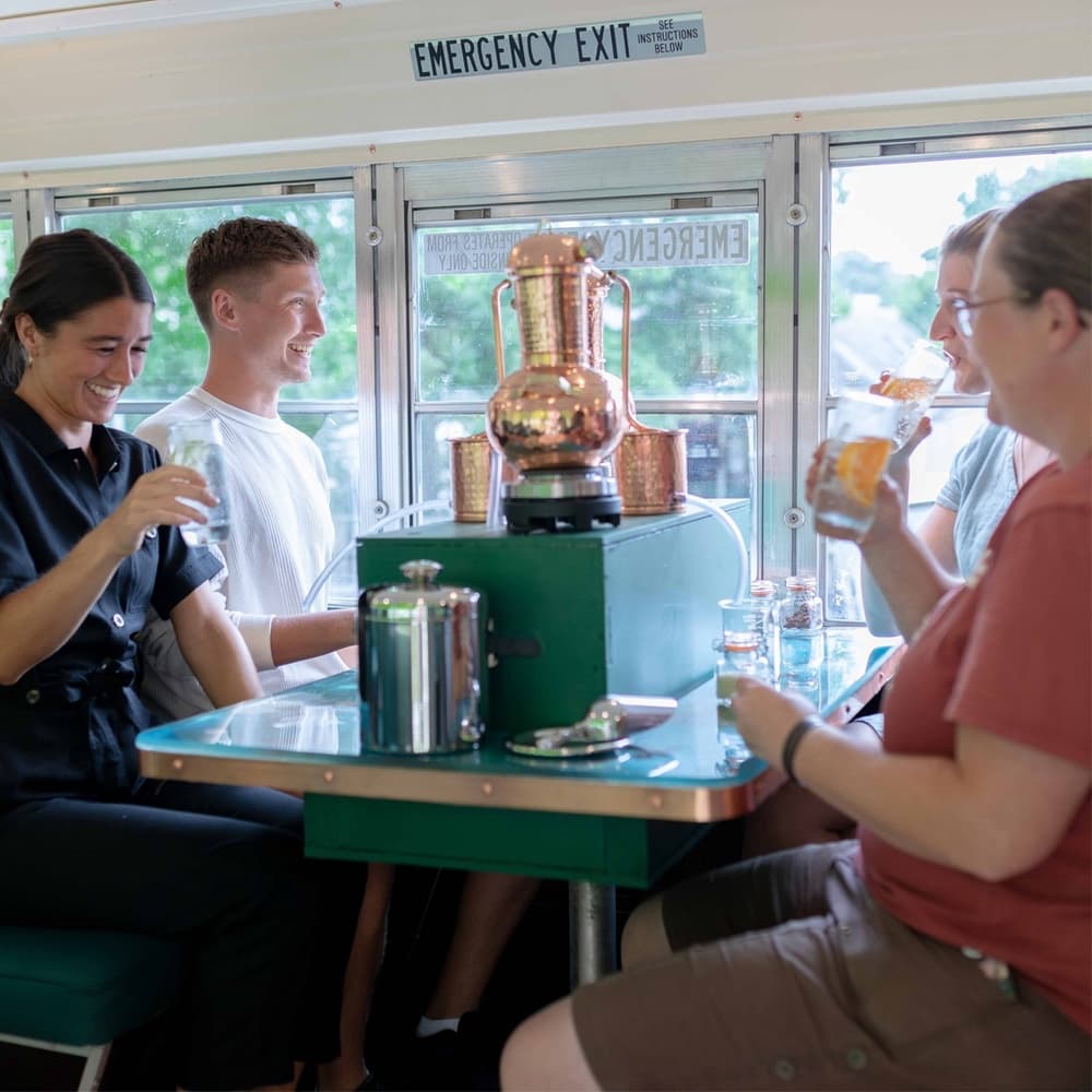 people on a rum making experience in devon on an american school bus