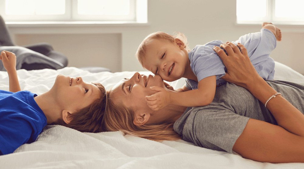 two children with their mum lying on the bed to illustrate ideas for mothers day gifts