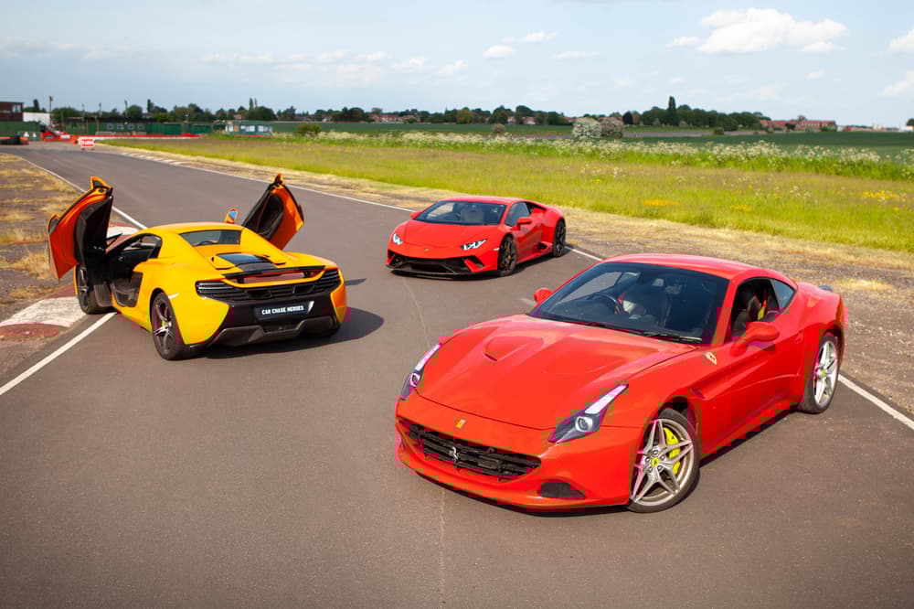 a yellow lamborghini and two red ferraris on a race track for a driving experience