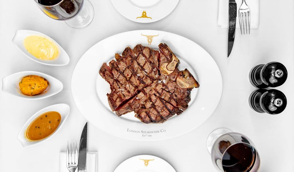 a close up on a plate of steak on a restaurant table with sauces on the side