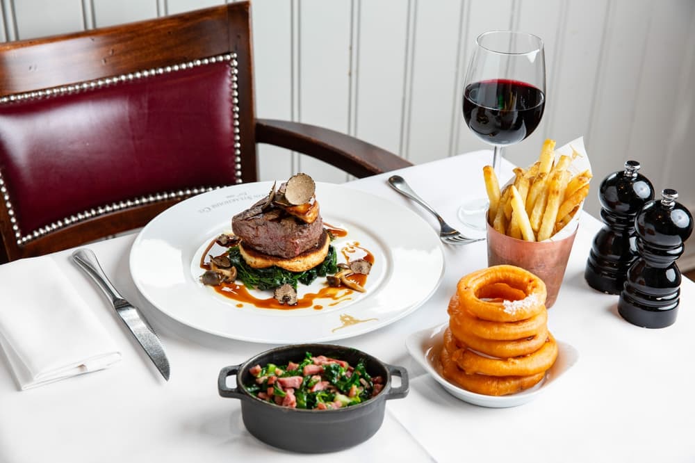 table set up with steak dinner and sides for a dining experience at marco pierre whites london steakhouse