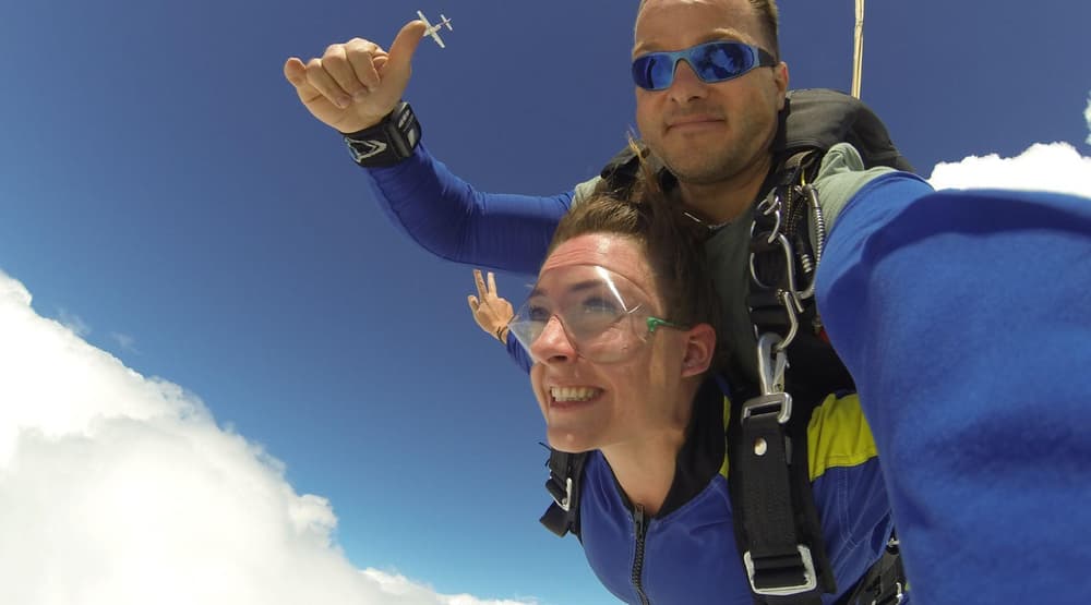a woman on a tandem skydive during freefall against a blue sky