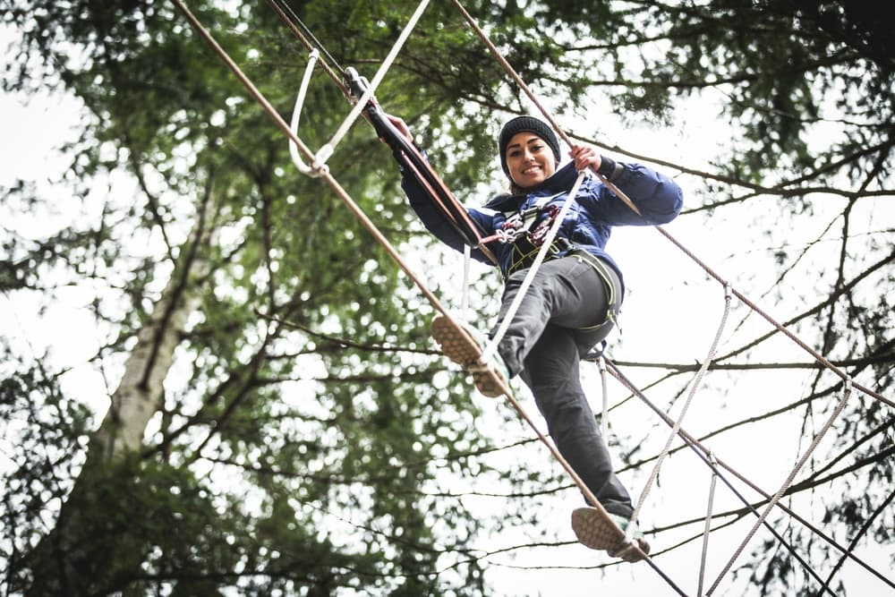 person walking a tight rope through trees on a zip safari experience day
