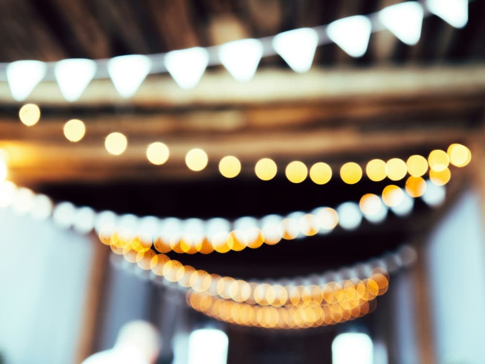 blurred out photo of strings of lights handing from a ceiling
