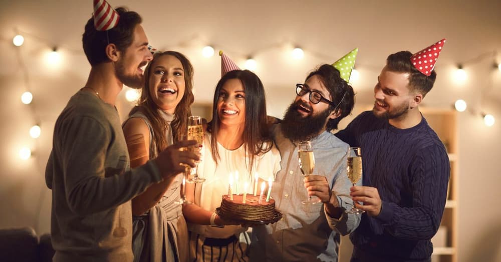 group of friends celebrating a birthday with a cake and candles
