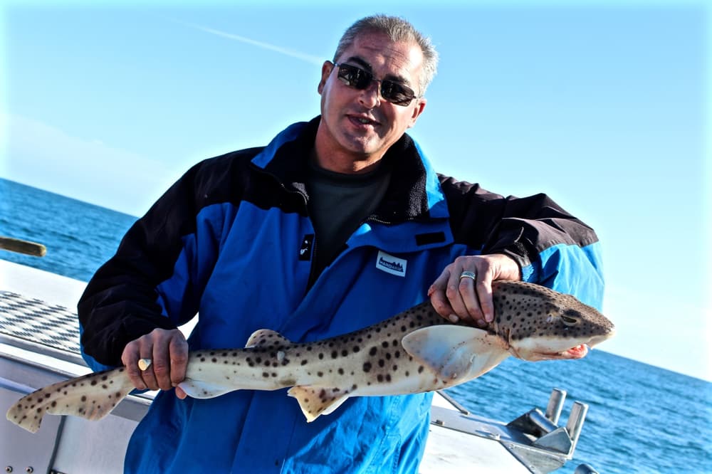 a man holding a fish caught on a deep sea fishing trip off the east sussex coast