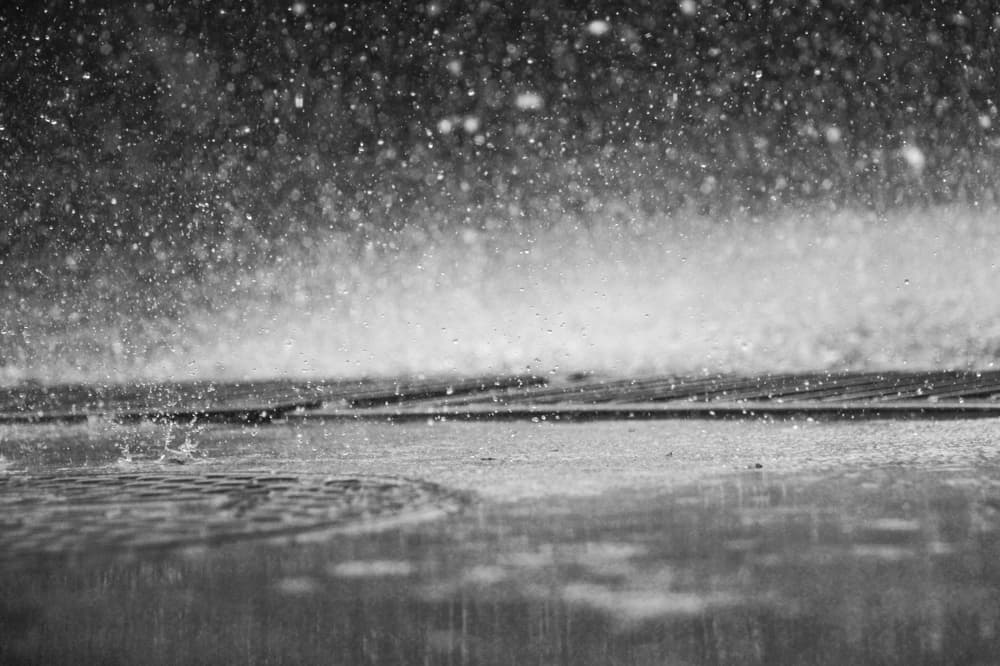 a black and white photo of raindrops bouncing off the pavement