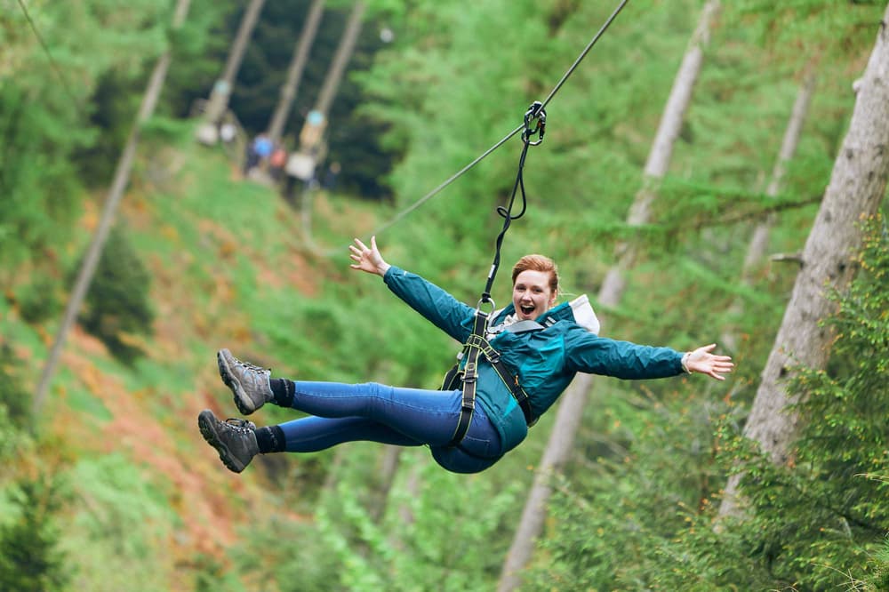 girl with arms outstretched on zip line at go ape zip trekking experience