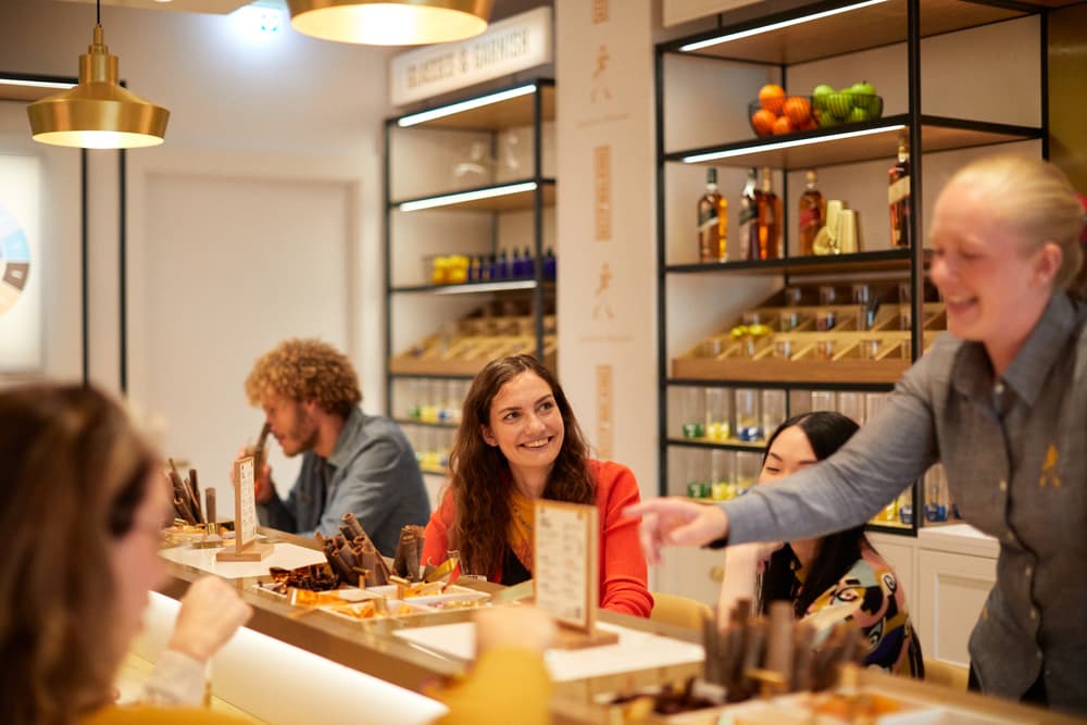 smiling woman sat at table learning about the flavours of whisky