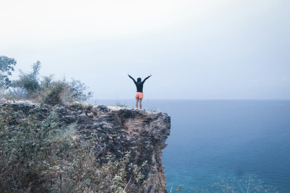 Lady standing on a rock with the sea in front of her