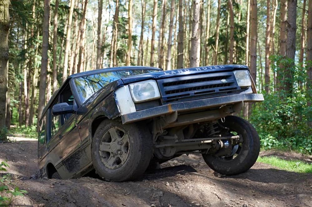 a landrover going up a bank on a woodland course on an off road driving experience