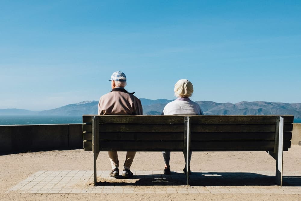 couple sitting on a bench overlooking countryside on a sunny day