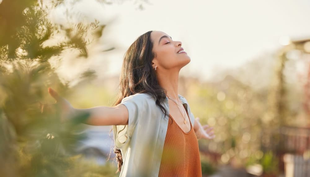 a woman with arms outstretched and head to the sky practicing mindfulness