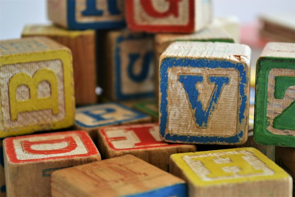 childrens wooden blocks with coloured letters in a pile