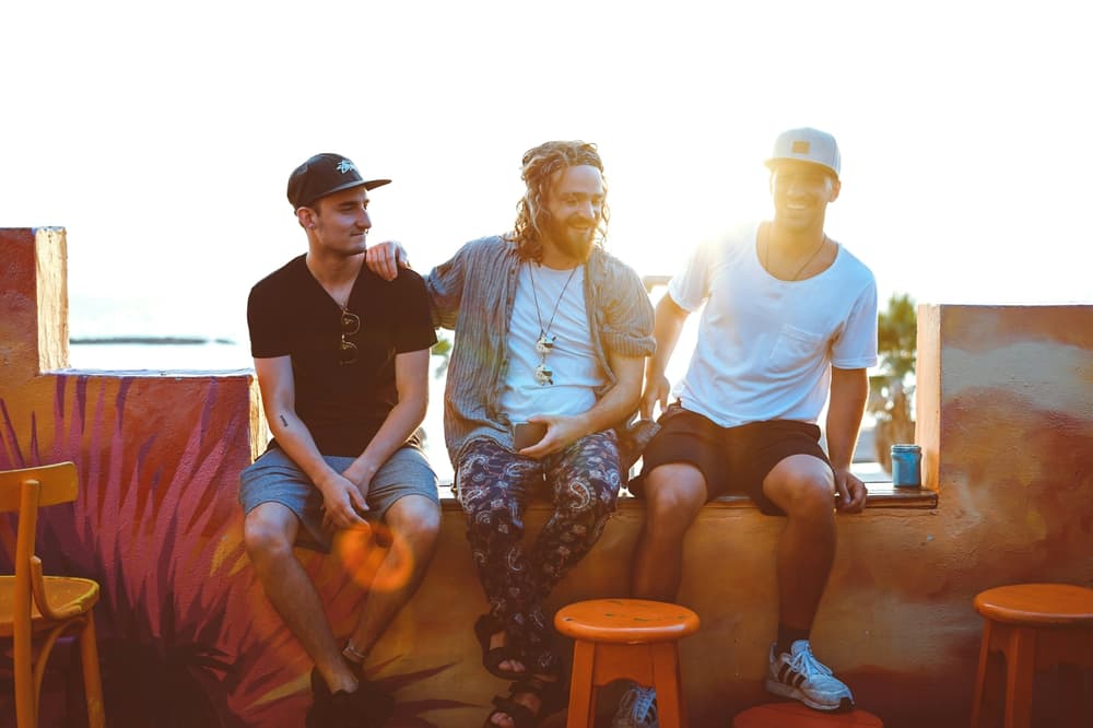 three men sitting in a bar area in the sunshine