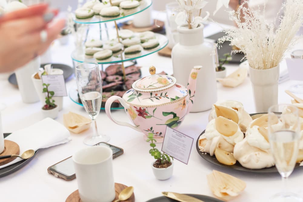 a table set up for afternoon tea on a white tablecloth with cakes and flowers to showcase the top afternoon tea venues in the uk