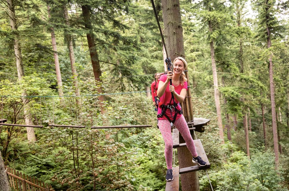 woman on bridge on treetop challenge course at go ape