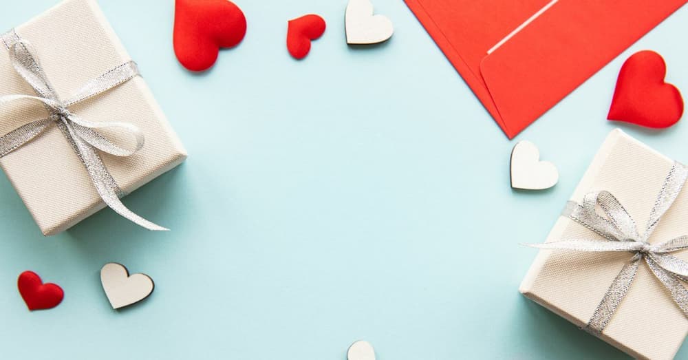 pale blue background with white present boxes and red cut out hearts to illustrate valentines day