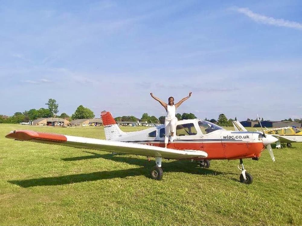 Woman standing on the wing of an aeroplane posing for a photo after a having a pilot lesson