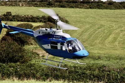 a blue and white helicopter flying over fields as part of a chopper experience